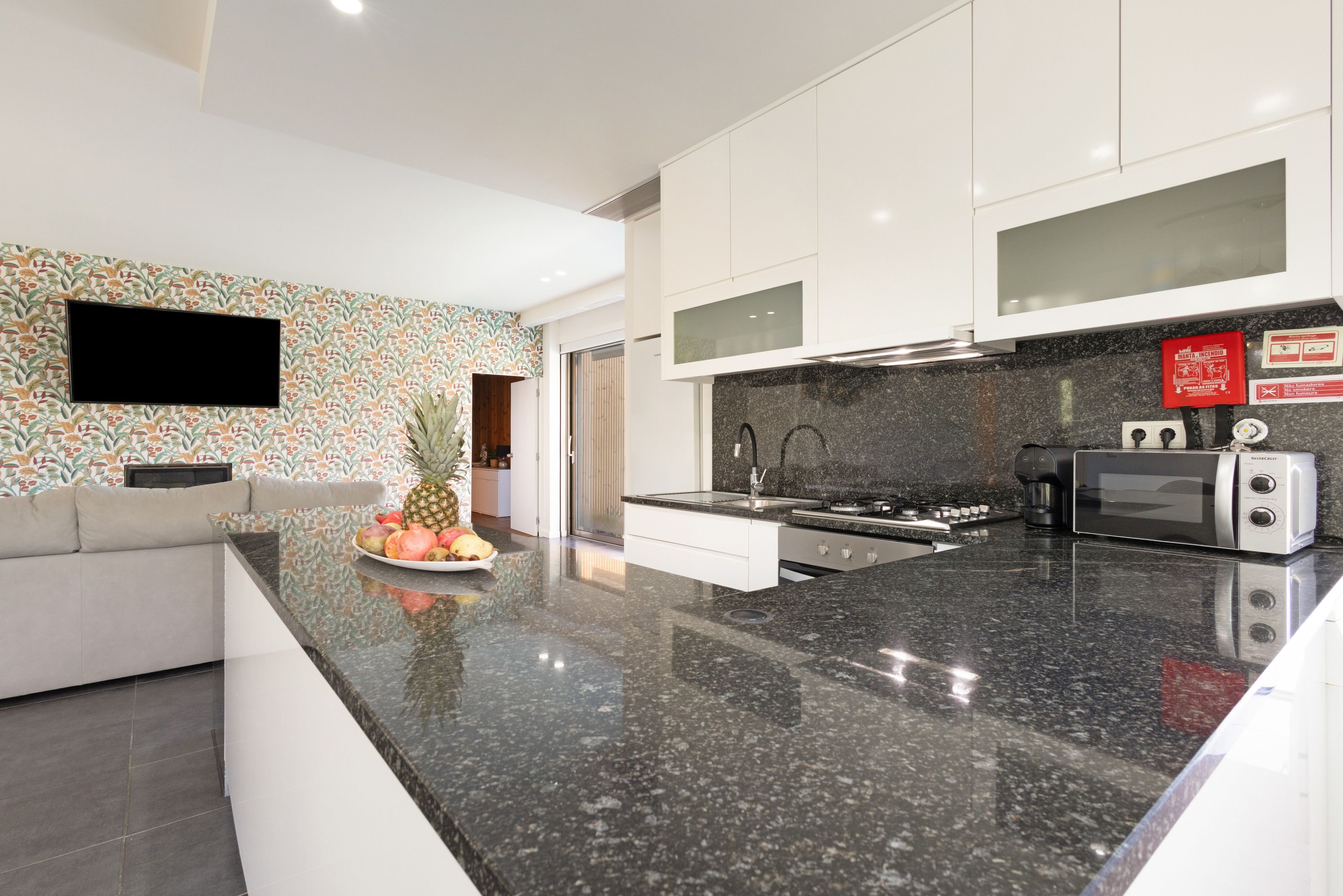 A modern kitchen with a granite countertop, stainless steel appliances, and a white cabinetry.