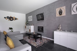 Een moderne woonkamer met een grijze bank, een zwarte salontafel en een witte kast.
