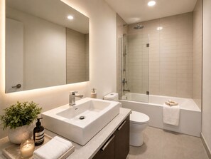 Uma casa de banho moderna com um espelho grande, uma sanita, uma lavatório retangular e uma cabine de duche com portas de vidro.