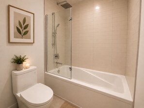 Une salle de bain comprenant des toilettes, une baignoire et un espace douche.