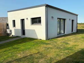 A modern, single-story building with a flat roof, large windows, and a small entrance.