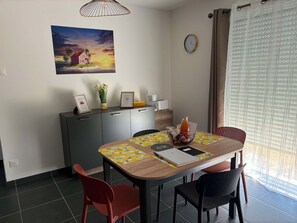 En matplats med ett träbord, stolar, en klocka och ett fönster med persienner.