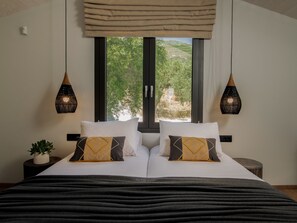 A bedroom with a bed, two bedside lamps, a window with a view of greenery, and a small plant on a bedside table. - Villa Verde Zante in Kallithea (Kallithea)