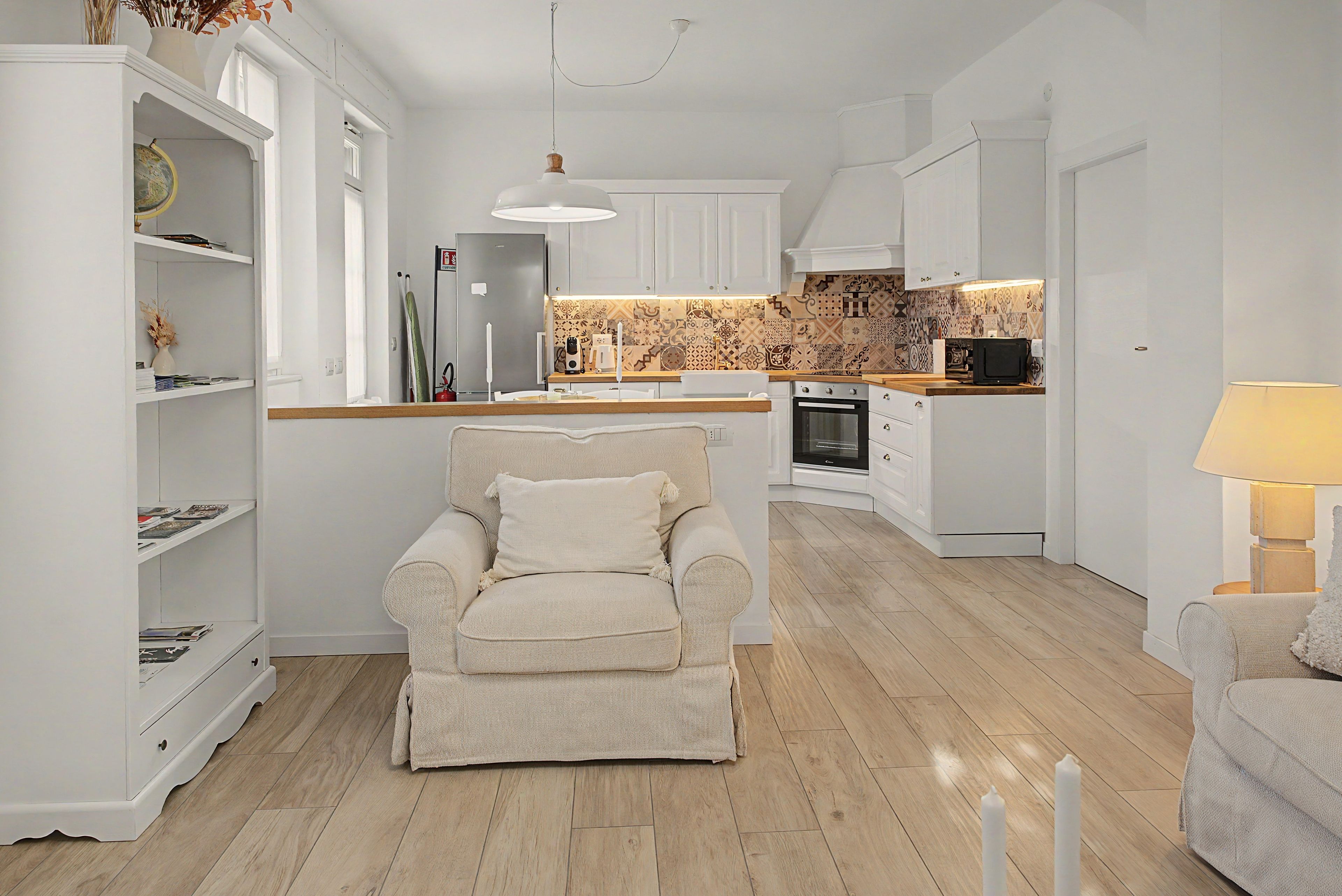 Una cucina moderna con mobili bianchi, un piano di lavoro in legno e un forno integrato.