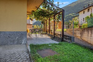 Ein Innenhof mit einer Pergola, Sitzgelegenheiten im Freien und Blick auf einen Berg.