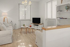 Un salon moderne avec un canapé, un téléviseur, une petite table et une bibliothèque.