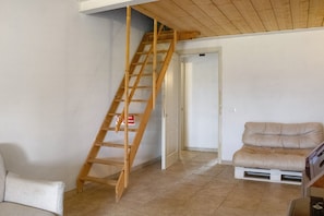 Ett rum med en trästege, en beige soffa och en vit dörr.