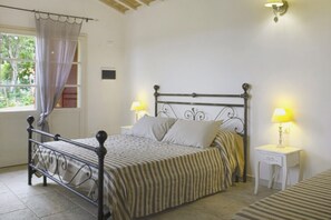 Ein Schlafzimmer mit einem Bett, zwei Nachttischen, einem Fenster mit Vorhängen und einer Lampe auf jedem Tisch.