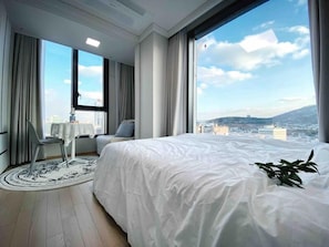 A modern hotel room with a large bed, a view of the cityscape, and a round table with a chair. - S Class (Seoul)