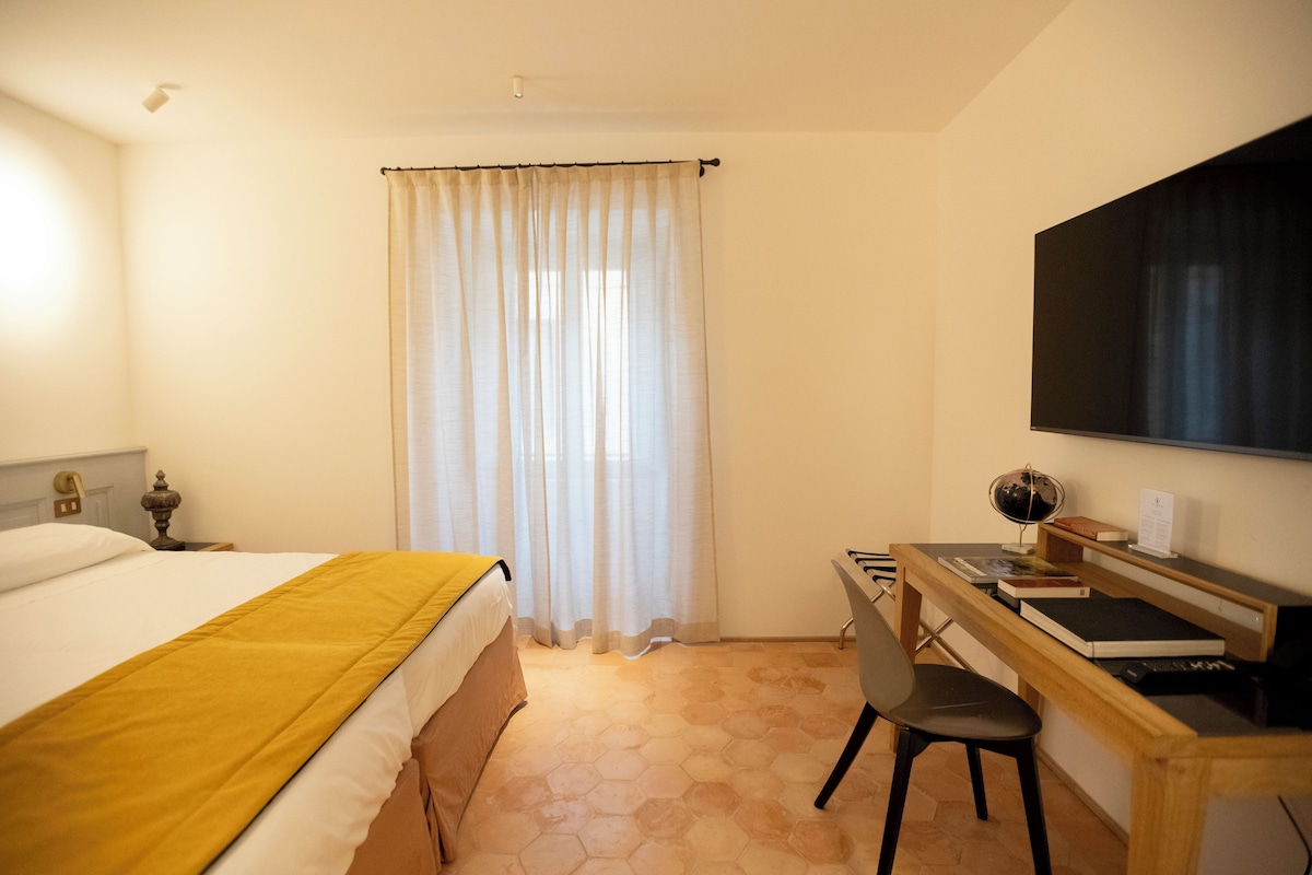 A hotel room with a bed, a desk, a chair, a globe, and a television.