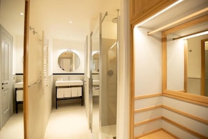 A modern bathroom with a glass shower enclosure, a vanity with a mirror, and a wooden floor. - Casa Bianconi (Norcia)