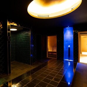 A modern bathroom with a tiled floor, a wall-mounted sink, and a ceiling light fixture. - Casa Bianconi (Norcia)