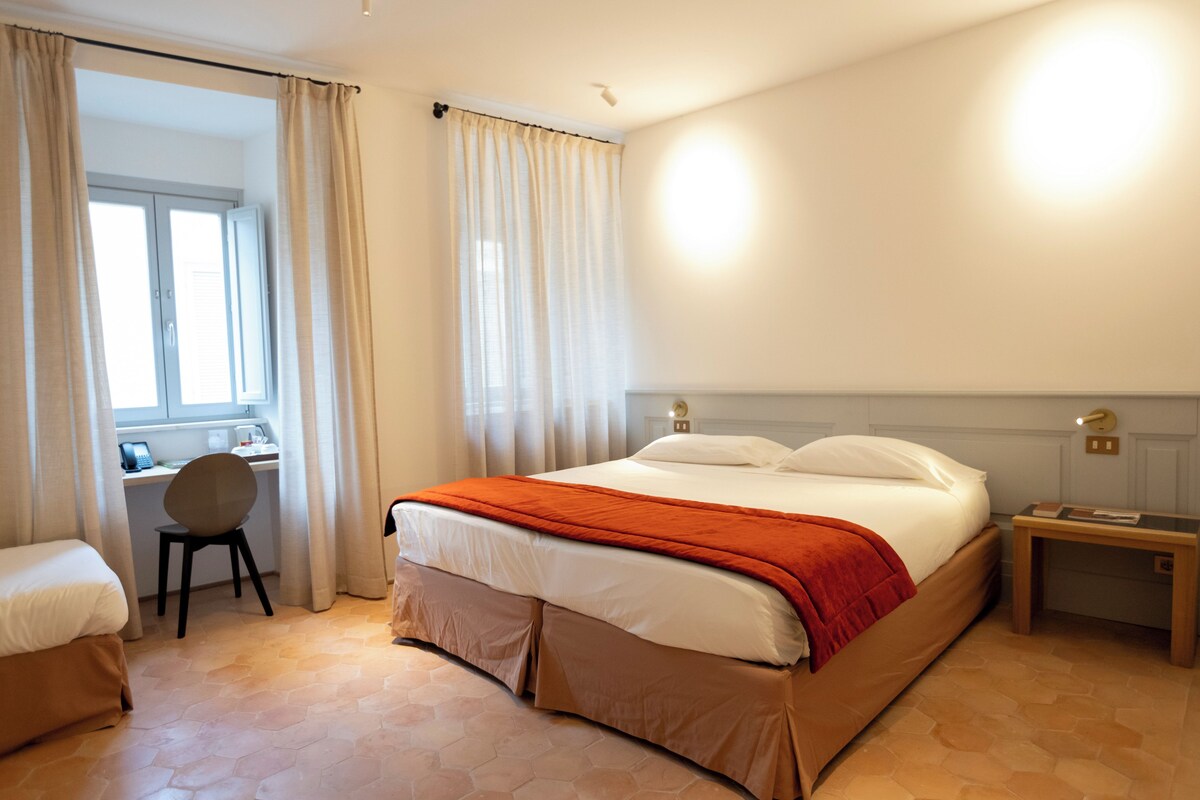 A hotel room with a bed, a desk, and a chair.