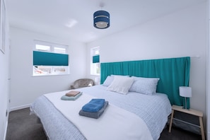 A hotel room with a bed, a chair, a nightstand, and a window with blinds. - Seaweed (Combe Martin)