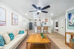 Ein modernes Wohnzimmer mit einer Couch, einem Couchtisch und einem Deckenventilator.
