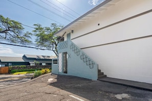 A building with a white exterior, a staircase with a geometric pattern, and a clear sky. - Kahaluu Beach Surf, Oceanview, 2bed,2bath, Lanai (Kailua-Kona)