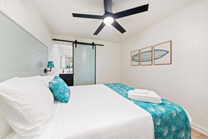 A hotel room with a bed, a ceiling fan, a bathroom with a mirror, and three framed artworks on the wall. - Kahaluu Beach Surf, Oceanview, 2bed,2bath, Lanai (Kailua-Kona)