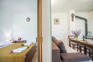 A hotel room with a bed, a small table with a lamp, a dining table with chairs, and a large mirror. - House with large garden, right next to the river (Žrnovnica)