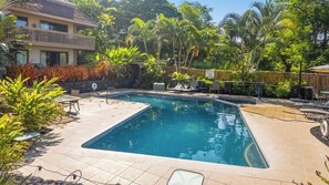 A rectangular swimming pool with a tiled deck, surrounded by lounge chairs and tropical plants. - Royal Kahili Oceanview Condo Sleeps 6 AC + Lanai (Kailua Kona)