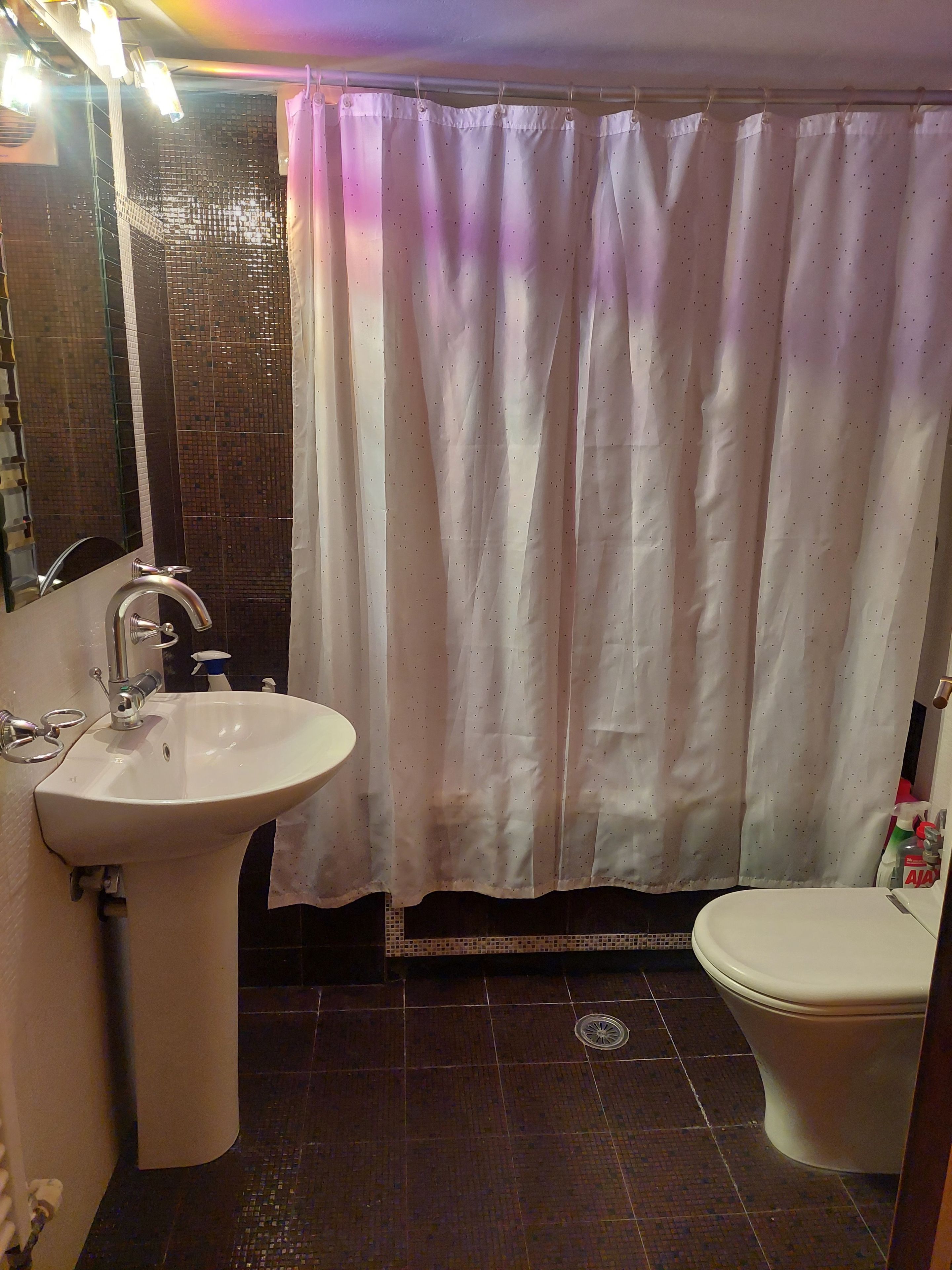 A bathroom with a white sink, a toilet, and a shower curtain.