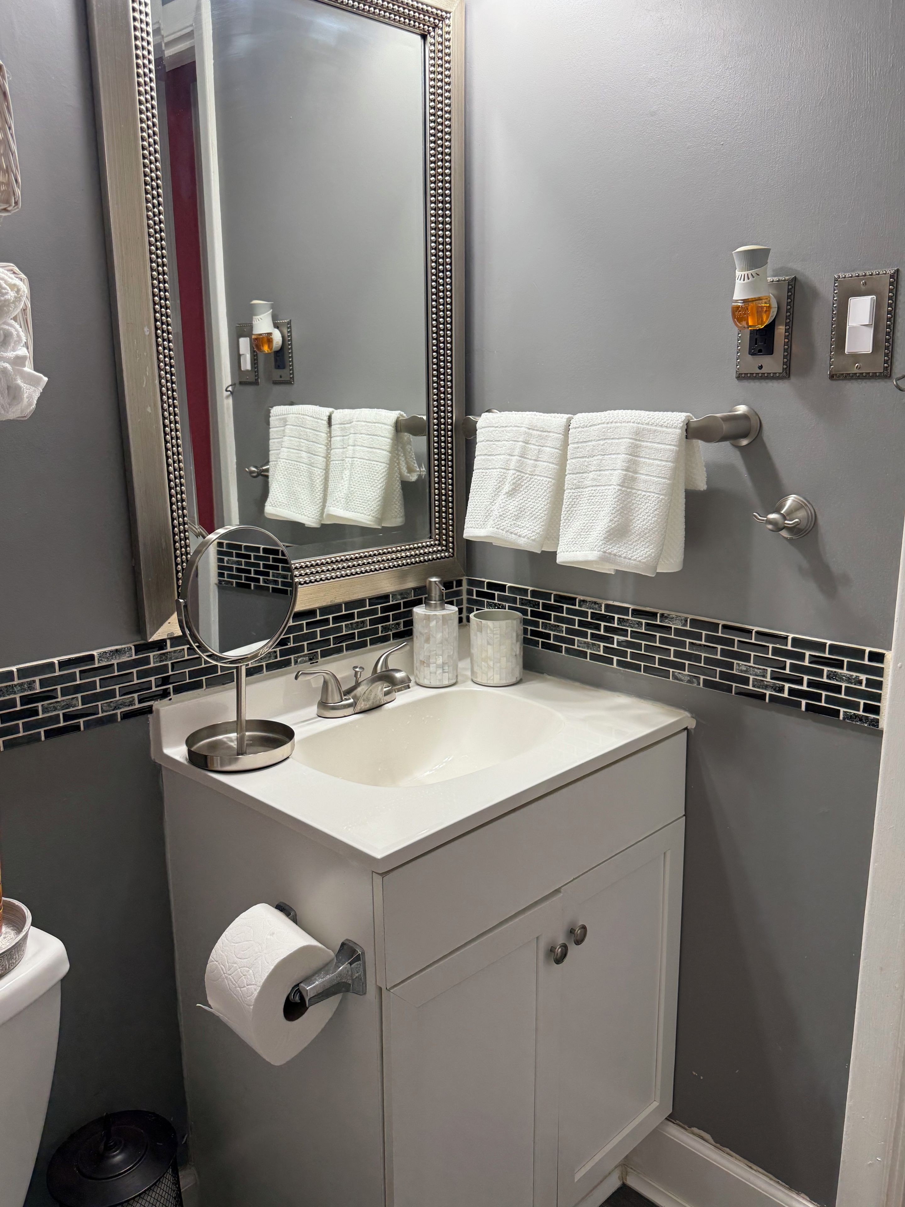 Et badeværelse med vask, spejl, håndklædestang og toilet.