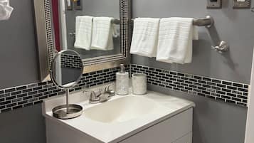 Et badeværelse med vask, spejl, håndklædestang og toilet.