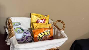 A wicker basket containing Lay's chips, Cheetos, and yogurt cups on a wooden table.