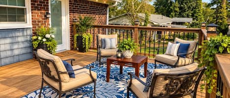 A deck with outdoor furniture, a potted plant, and a house in the background.