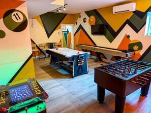 A room with a foosball table, a table tennis table, and a foosball table with a ball rack. - Arden Legacy Retreat: Pool, Sauna, Hot Tub, Game Room, Theater (Avery Creek)