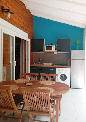 A kitchen with a dining area, wooden cabinets, a microwave, a washing machine, and a refrigerator. - Cannelle cottage in Deshaies. Swimming pool. Beach 400m away (Deshaies)