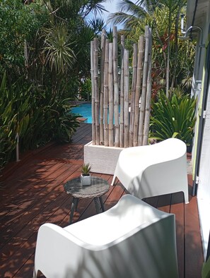A patio area with a pool, white chairs, and a bamboo fence. - Cannelle cottage in Deshaies. Swimming pool. Beach 400m away (Deshaies)