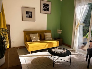 A living room with a sofa, a coffee table, and a window with curtains. - Cannelle cottage in Deshaies. Swimming pool. Beach 400m away (Deshaies)