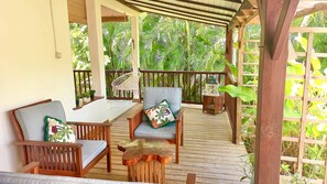 A covered outdoor seating area with wooden furniture and a view of lush greenery. - Bamboo Cottage in Deshaies. Swimming pool. Beach 400m away (Deshaies)