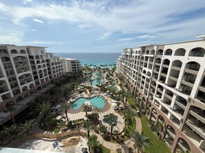 Et resort med flere bygninger, en central pool og udsigt over havet.