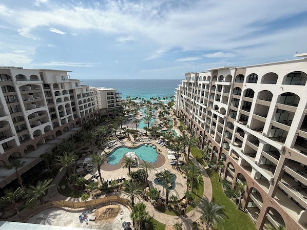 Un resort con varias construcciones, una piscina central y vistas al océano.
