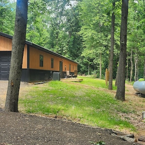 Eine Holzhütte mit einer Terrasse, umgeben von einem bewaldeten Gebiet.