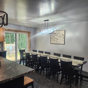 Comedor con una larga mesa, sillas y una lámpara moderna.