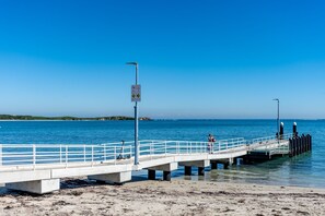 A pier extending into the sea with a clear sky above. - Olive & Ochre | Warm Coastal Retreat (Shoalwater)