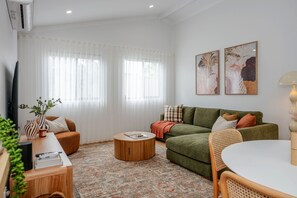 Ein Wohnzimmer mit einer Couch, einem runden Couchtisch, einem Fernseher und einer Lampe.