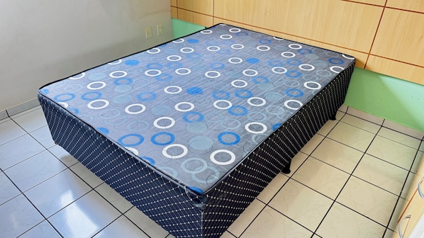 Una mesa pequeña y cuadrada con mantel estampado, base de malla negra y suelo de baldosas.