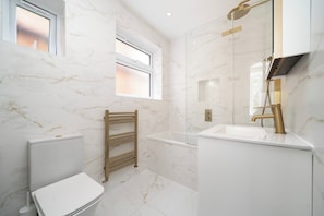 Ein modernes Badezimmer mit Toilette, Badewanne und Waschbecken.