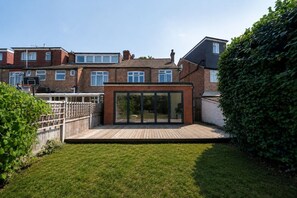 Il s’agit d’une propriété résidentielle dotée d’une cour arrière clôturée, d’un panier de basketball et d’un patio moderne à espace clos en verre.