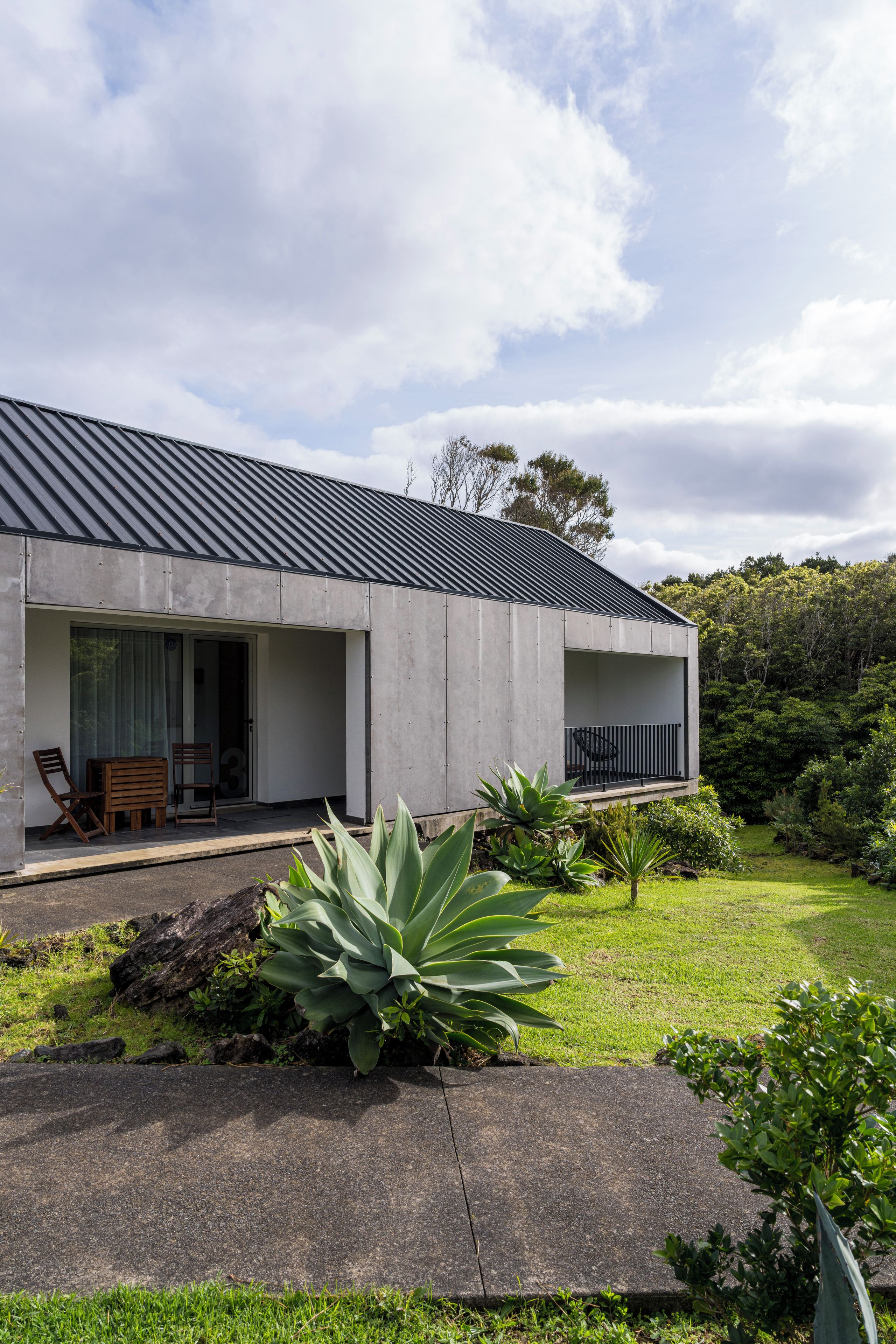 A modern house with a flat roof, large windows, and a balcony.