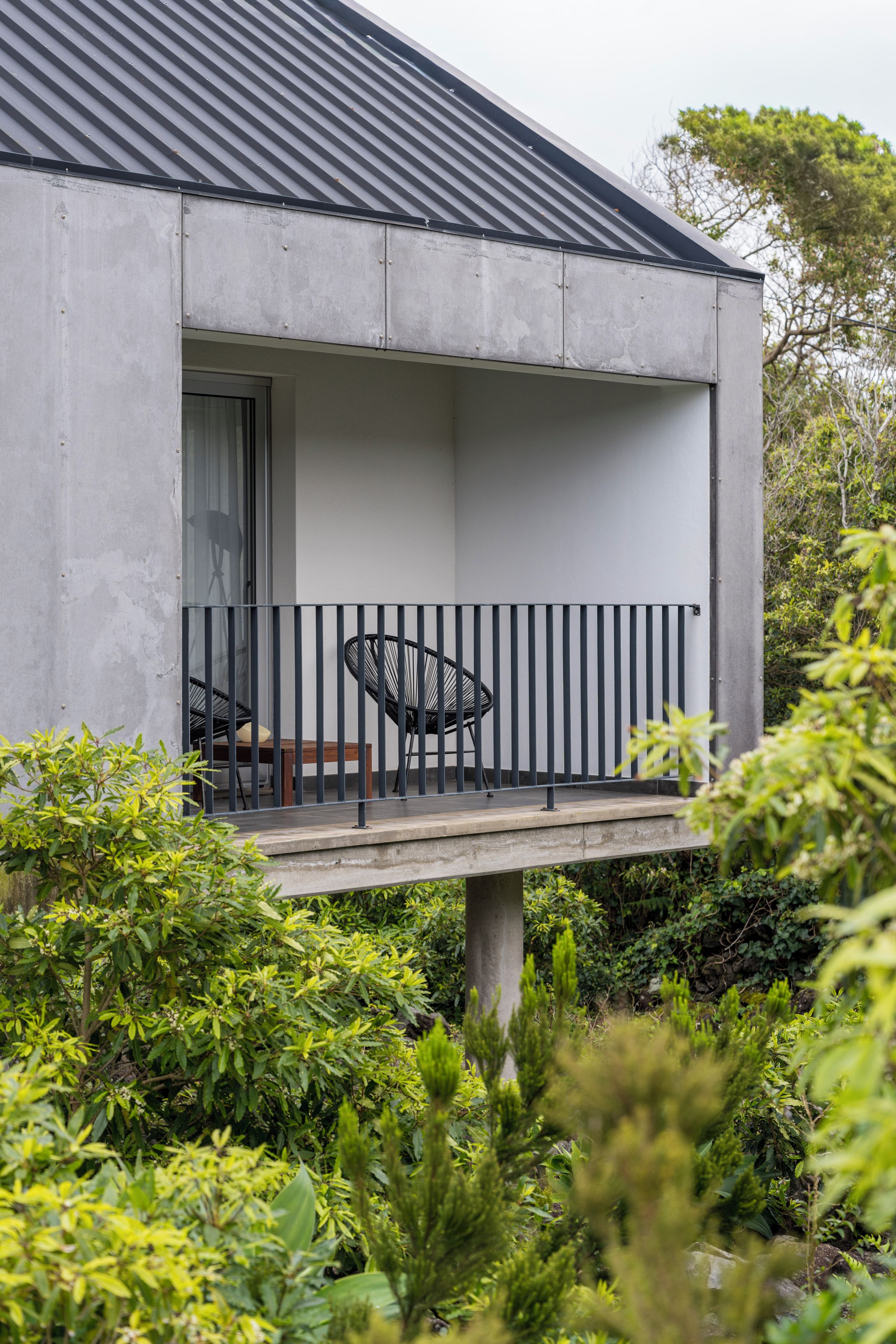 A modern building with a balcony, a chair, and a table.