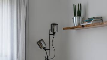 Una sala de estar con un sofá gris, una lámpara de pie, una planta y una estantería.