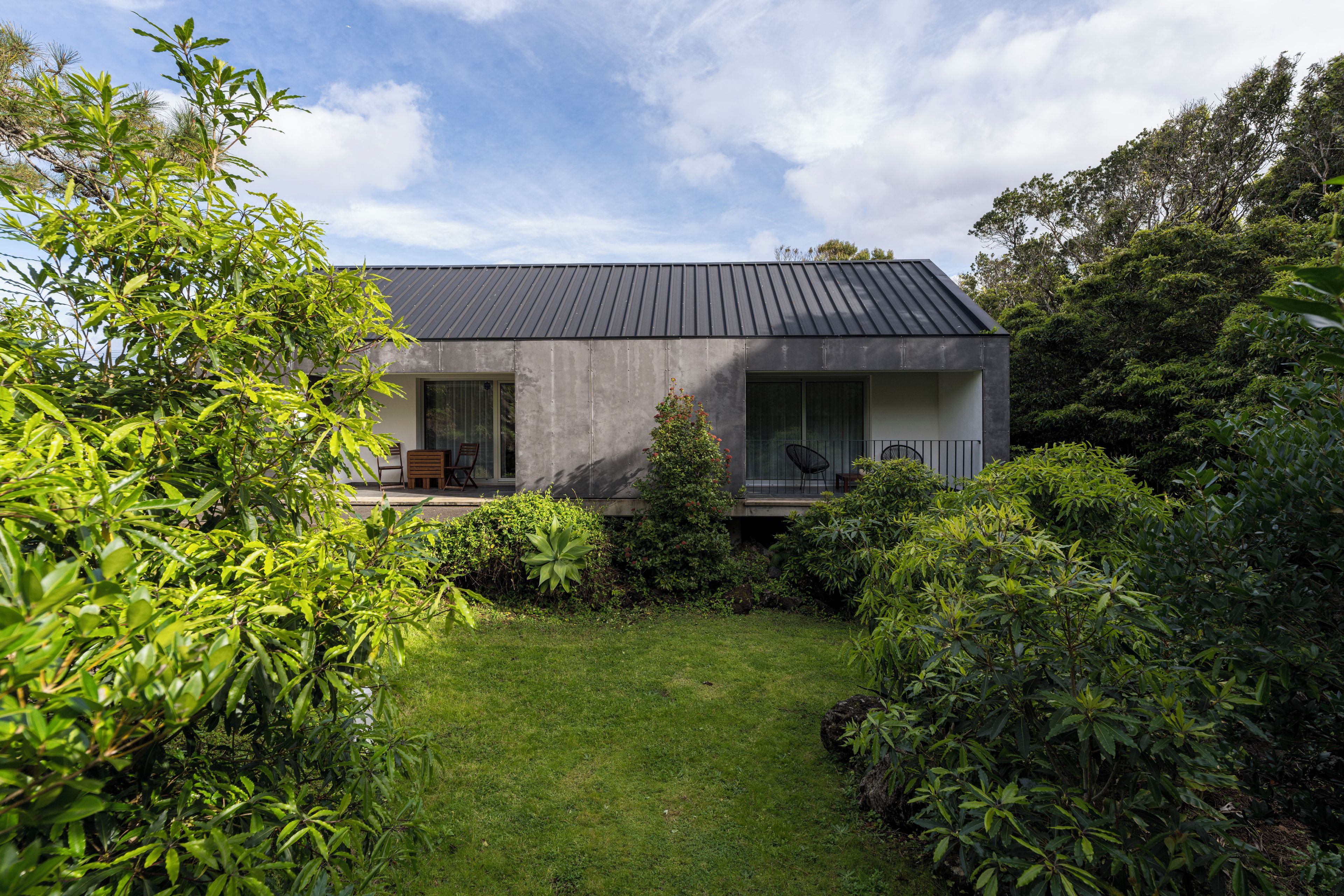 Et moderne hus med fladt tag, store vinduer og en velplejet have.