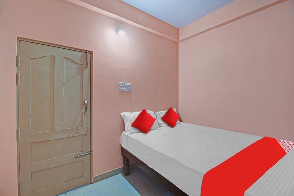 A bedroom with a single bed, a door, and a wall socket.