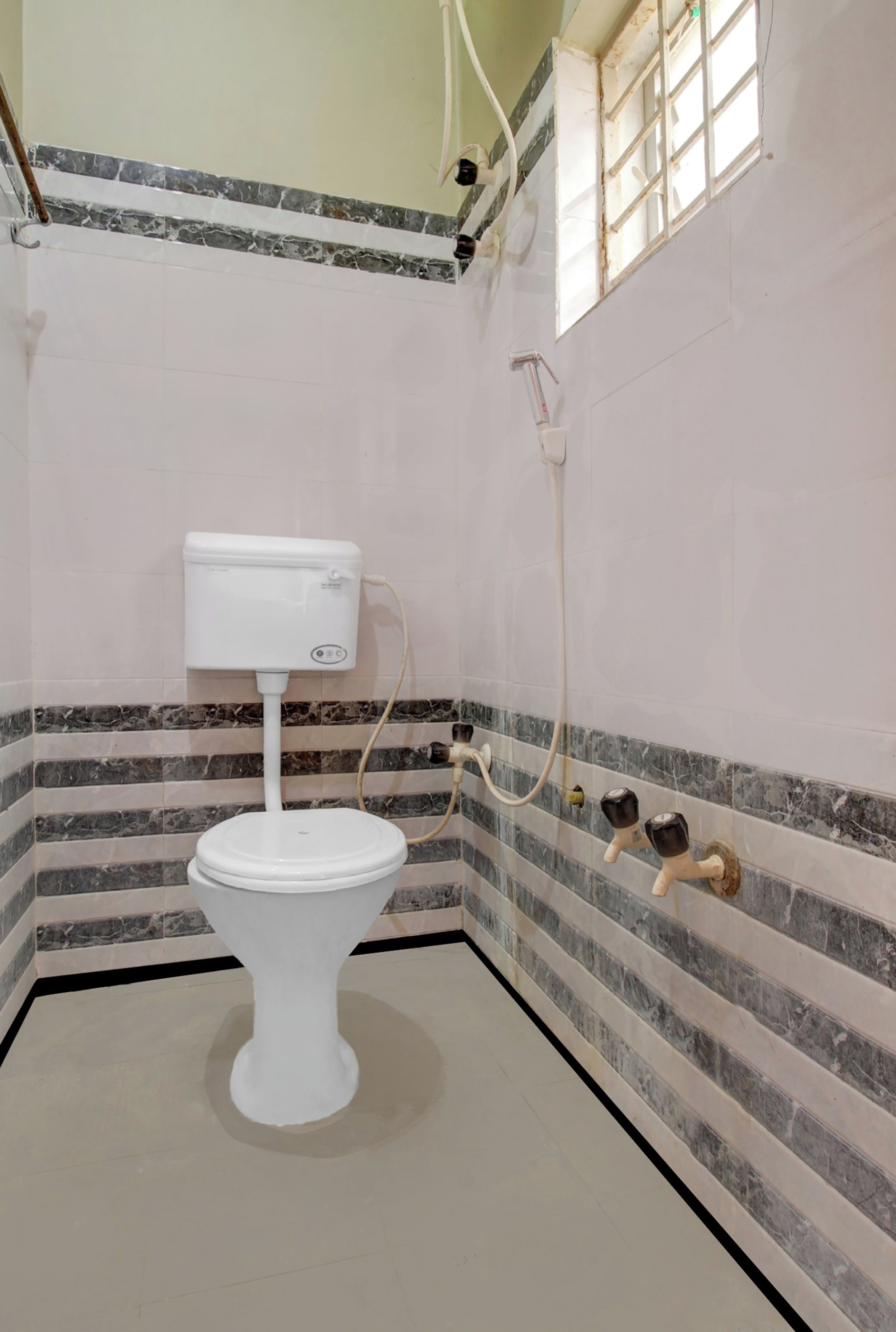 A small, basic bathroom with a toilet, a shower, and a window.