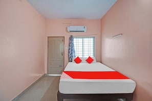 Una habitación con cama, ventana con cortinas, aire acondicionado y una puerta.