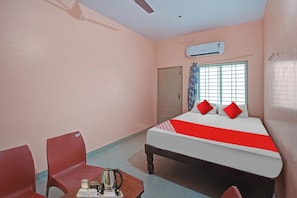 A hotel room with a bed, a chair, a table with a kettle, and an air conditioning unit. - Hotel O Central Bus Stop Bagepalli (Bagepalli)